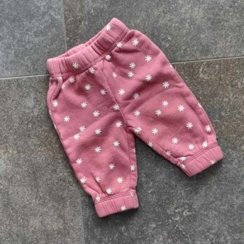 Pantalon rose à fleurs blanches.

Ceinture élastique